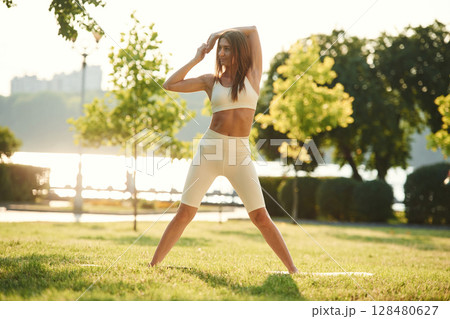 White sportive clothes. Beautiful young woman is in the park at sunny daytime White sportive clothes. Beautiful young woman is in the park at sunny daytime 128480627