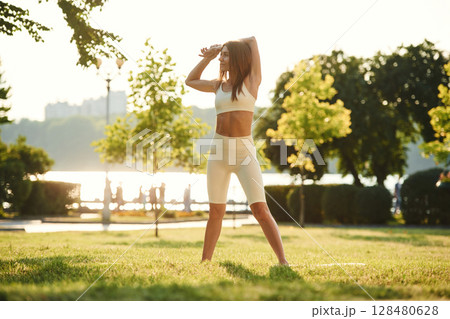 White sportive clothes. Beautiful young woman is in the park at sunny daytime White sportive clothes. Beautiful young woman is in the park at sunny daytime 128480628