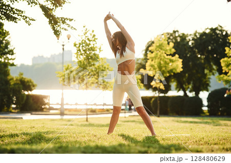 White sportive clothes. Beautiful young woman is in the park at sunny daytime White sportive clothes. Beautiful young woman is in the park at sunny daytime 128480629