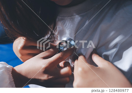 Cropped image of male doctor's hand using stethoscope to examining heartbeat and symptom of patient while talking 128480977