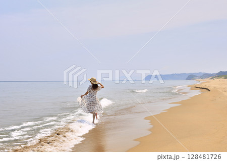 波打ち際を歩く女性 128481726