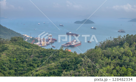July 13 2025 a Coastal Port with Cargo Vessels and Lush Green Hills July 13 2025 a Coastal Port with Cargo Vessels and Lush Green Hills 128482334