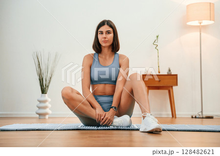 On yoga mat. Pretty woman in sportive clothes have fitness day indoors On yoga mat. Pretty woman in sportive clothes have fitness day indoors 128482621