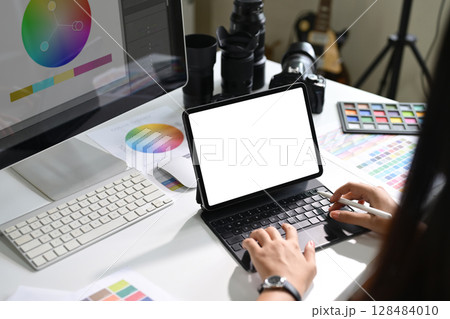 Photographer working on digital tablet with color charts and editing tools on desk Photographer working on digital tablet with color charts and editing tools on desk 128484010