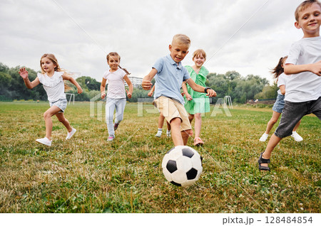 Soccer ball, playing together. Kids are having fun on the field at daytime 128484854