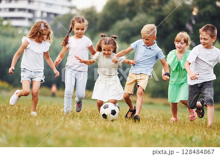 Playing soccer. Kids are having fun on the field at daytime together Playing soccer. Kids are having fun on the field at daytime together 128484867