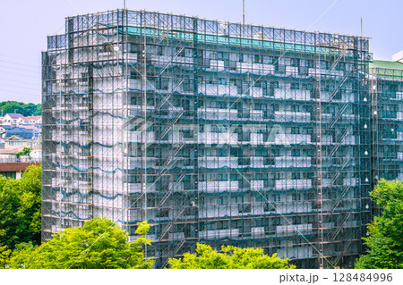 日本の横浜都市景観 マンションの補修や点検等、足場や防護ネットなど。ネットの外に衛星アンテナが 日本の横浜都市景観 マンションの補修や点検等、足場や防護ネットなど。ネットの外に衛星アンテナが 128484996