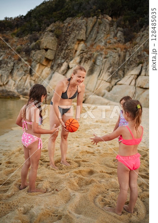 Family fun at the beach with kids playing basketball by the shore 128485035