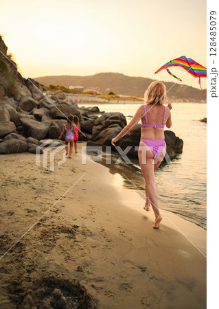 Family bonding time on the beach with colorful kite fun at sunset 128485079