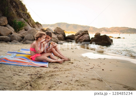Siblings share joyful moments enjoying ice cream by the shore Siblings share joyful moments enjoying ice cream by the shore 128485234