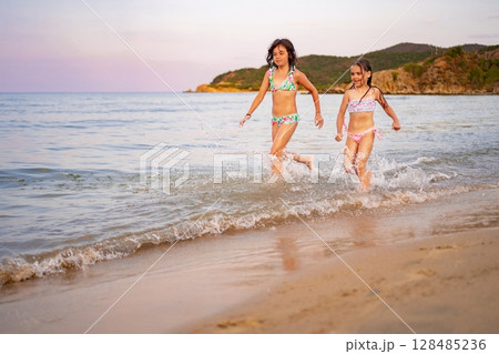 Siblings enjoying a playful day at the beach during sunset Siblings enjoying a playful day at the beach during sunset 128485236