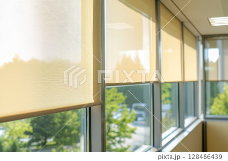 Motorized blinds beige color closeup in the window opening. Automatic home roller shades and curtains. Modern bottom up privacy shades half raised on apartment windows. Windowsill with plants 128486439