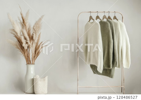 Stylish chic cardigans in pastel beige, green, brown and cream colors hanging on display. Autumn collection. Fall Fashion Wardrobe. Knit garments on clothes rack in a store. Woolen female wear items. Stylish chic cardigans in pastel beige, green, brown and cream colors hanging on display. Autumn collection. Fall Fashion Wardrobe. Knit garments on clothes rack in a store. Woolen female wear items. 128486527