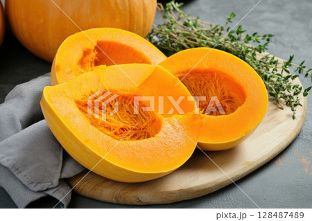 Cutting Fresh Pumpkins on Board. Baked pumpkin. Sliced raw Cucurbita maxima and spices for preparing soup, warm salad, fall dish. Thanksgiving food. Roasted vegetable in olive oil salt pepper, herbs. 128487489