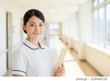 病院の明るい廊下で白衣を纏い、笑顔で立つ女性看護師 128488128