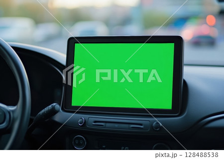 Navigator with green screen in the car dashboard. GPS module. Driver using smart phone with green background. Man steering wheel, driving on highway with smartphone navigation. Digital display monitor 128488538