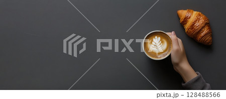 Person Hands Holding Coffee Cappuccino Cup. Composition with Coffee Latte with Milk Foam Art and Tasty Fresh Croissant on a Gray Table. Food series. Breakfast with Fresh Baked Pastry. Closeup top view 128488566