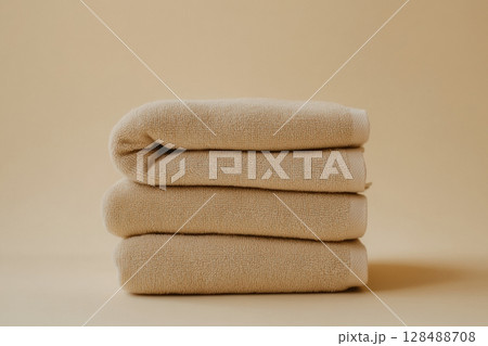 Heap of towels. Bath towels pile stack on beige background. Shadows. Copy space. Soft, plain towels in pastel colored for bath and spa settings, relaxation and comfort. Pile of clean towels 128488708