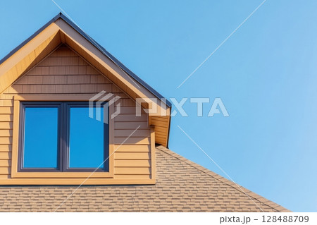 House Exterior. Roof Window. Second floor among blue sky. Mansard attic. Newly build houses. Gable roof with skylight, asphalt roofing, shingles. Residential Home. Vinyl Siding. Polymeric roof-tiles 128488709