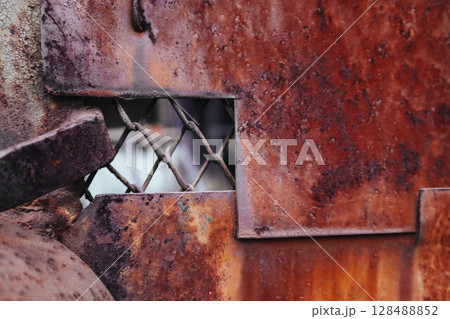 Old aged metal gate closed front view. Rusty doors with paint peeled out close up view. Closed private area. Abstract red brown metal sheet, panel. 128488852