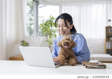ノートパソコンで作業をするミドル女性と愛犬　在宅勤務イメージ 128489039
