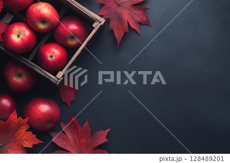 Autumn background. Fall banner with colorful leaves, crate of apple harvest on a dark surface, top view. Fresh red apples crop. Autumnal fruits basket. Free space for text. Thanksgiving seasonal decor 128489201
