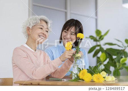 フラワーアレンジメントを楽しむシニア女性と介護スタッフ 128489517