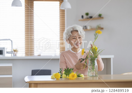 自宅で花をいけるシニア女性 128489519