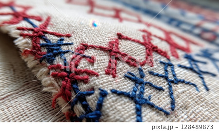 Close-up of intricate red and blue cross-stitch embroidery on fabric 128489873