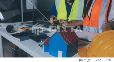 Closeup of team of industrial engineers meeting analyze machinery blueprints consult project on table in manufacturing factory. Working in manufacturing plant or production plant. 128490726