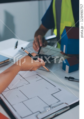 Closeup of team of industrial engineers meeting analyze machinery blueprints consult project on table in manufacturing factory. Working in manufacturing plant or production plant. 128490757