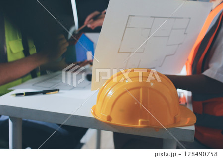 Closeup of team of industrial engineers meeting analyze machinery blueprints consult project on table in manufacturing factory. Working in manufacturing plant or production plant. Closeup of team of industrial engineers meeting analyze machinery blueprints consult project on table in manufacturing factory. Working in manufacturing plant or production plant. 128490758