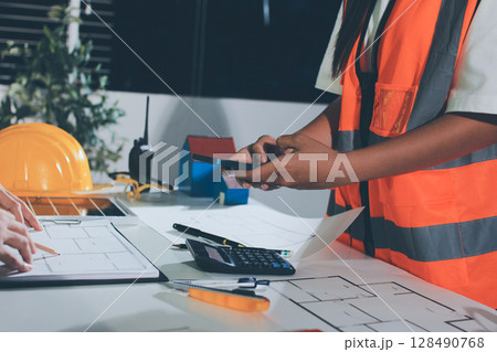 Closeup of team of industrial engineers meeting analyze machinery blueprints consult project on table in manufacturing factory. Working in manufacturing plant or production plant. Closeup of team of industrial engineers meeting analyze machinery blueprints consult project on table in manufacturing factory. Working in manufacturing plant or production plant. 128490768