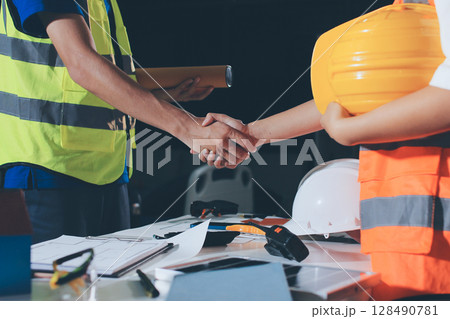 Closeup of team of industrial engineers meeting analyze machinery blueprints consult project on table in manufacturing factory. Working in manufacturing plant or production plant. 128490781