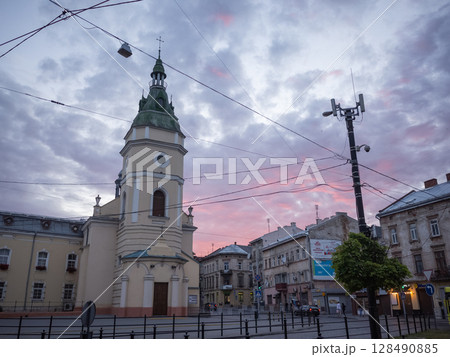 【ウクライナ】リヴィウ旧市街に建つカトリック教会の外観と赤く色づいた夕暮れの曇り空 【ウクライナ】リヴィウ旧市街に建つカトリック教会の外観と赤く色づいた夕暮れの曇り空 128490885