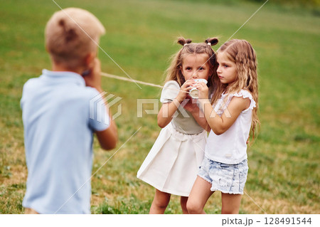 Talking, using string can toy. Kids are having fun on the field at daytime together Talking, using string can toy. Kids are having fun on the field at daytime together 128491544