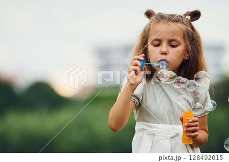 Portrait of little girl that is playing with bubbles outdoors 128492015