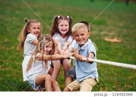 Game of strength. Tug of war game. Kids are having fun on the field at daytime together 128492066