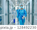 Confident healthcare workers walking in hospital corridor. 128492230
