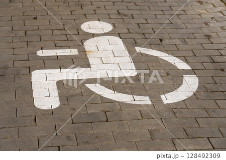 A clear wheelchair access symbol is prominently painted on the pavement in an urban setting, emphasizing the importance of accessibility for all A clear wheelchair access symbol is prominently painted on the pavement in an urban setting, emphasizing the importance of accessibility for all 128492309