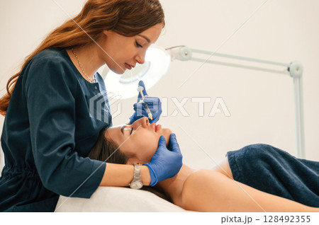 Cosmetologist does injection for lips augmentation. Women's cosmetology in the beauty salon Cosmetologist does injection for lips augmentation. Women's cosmetology in the beauty salon 128492355