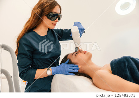 Lying down. Getting photo rejuvenation procedure at cosmetology clinic 128492373