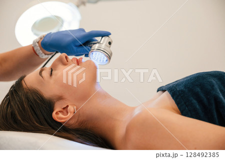Getting photo rejuvenation procedure at cosmetology clinic. Women in beauty salon Getting photo rejuvenation procedure at cosmetology clinic. Women in beauty salon 128492385