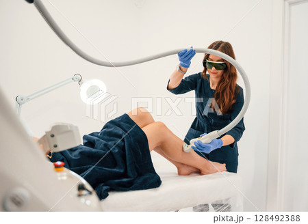 Procedure on the legs. Getting photo rejuvenation at cosmetology clinic. Women in beauty salon 128492388