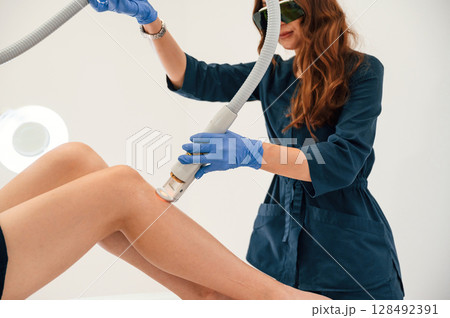 Procedure on the legs. Getting photo rejuvenation at cosmetology clinic. Women in beauty salon 128492391