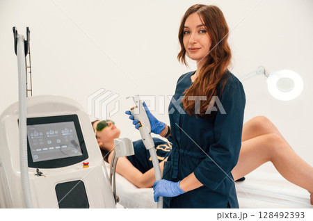 Modern device. Getting photo rejuvenation procedure at cosmetology clinic. Women in beauty salon Modern device. Getting photo rejuvenation procedure at cosmetology clinic. Women in beauty salon 128492393