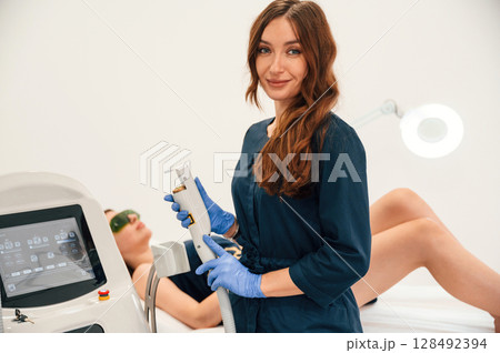 Modern device. Getting photo rejuvenation procedure at cosmetology clinic. Women in beauty salon Modern device. Getting photo rejuvenation procedure at cosmetology clinic. Women in beauty salon 128492394