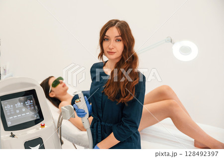 Standing and holding device. Getting photo rejuvenation procedure at cosmetology clinic. Women in beauty salon 128492397