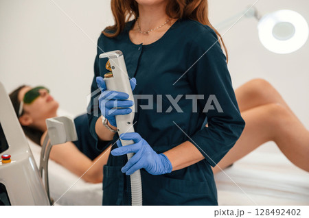 Holding device. Getting photo rejuvenation procedure at cosmetology clinic. Women in beauty salon 128492402