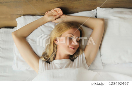Woman sleeping lying in bed on white soft comfortable pillow in bedroom at home Woman sleeping lying in bed on white soft comfortable pillow in bedroom at home 128492497